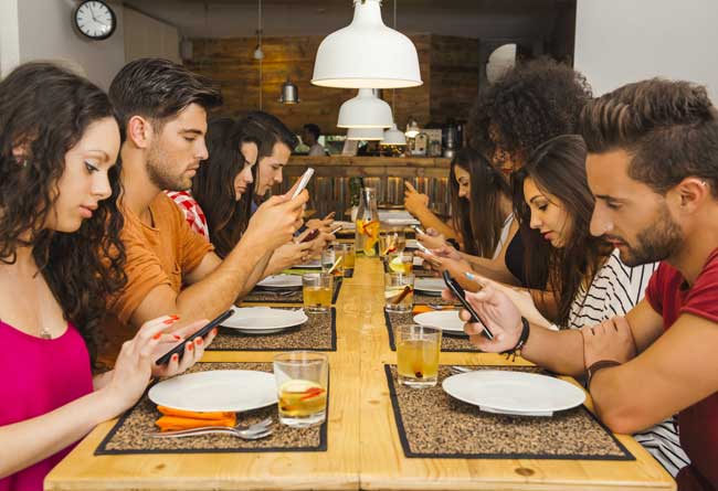 Group of friends at a restaurant occupied with cell phones