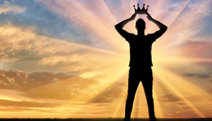 Silhouette of man placing crown on his own head