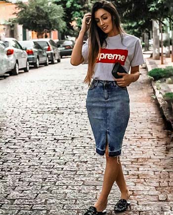 Girl wearing a knee-length denim skirt and t-shirt while walking down a street