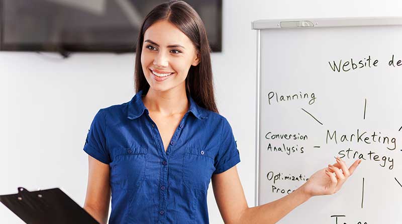 Young female image consultant pointing at strategy on whiteboard behind her