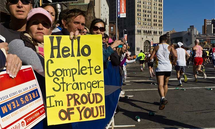 Crowed of people holding up a sign that reads: "Hello complete stranger, I'm proud of you!" at the New York Marathon