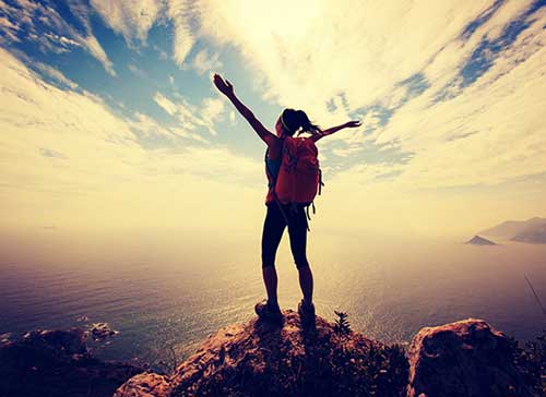 Woman standing on a mountaintop with arms raised
