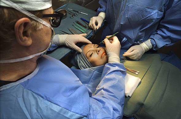 A male plastic surgeon and his team in an operating theatre