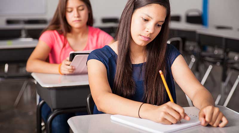 Two girls writing their examinations in a classroom