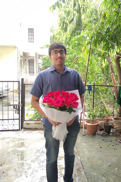 Chaitanya Iyer standing with a bouquet of roses
