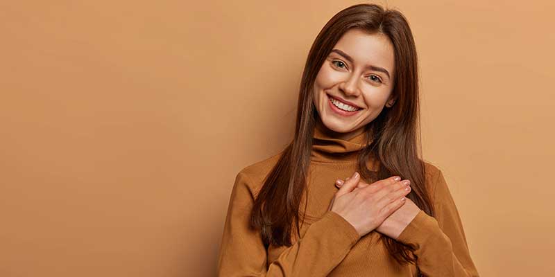 Cheerful young woman with hands over her heart in gratitude