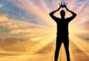Silhouette of a man holding a crown above his head