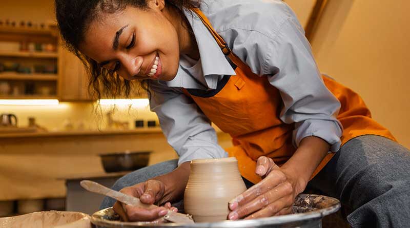 Smiling woman doing pottery using a potter's wheel