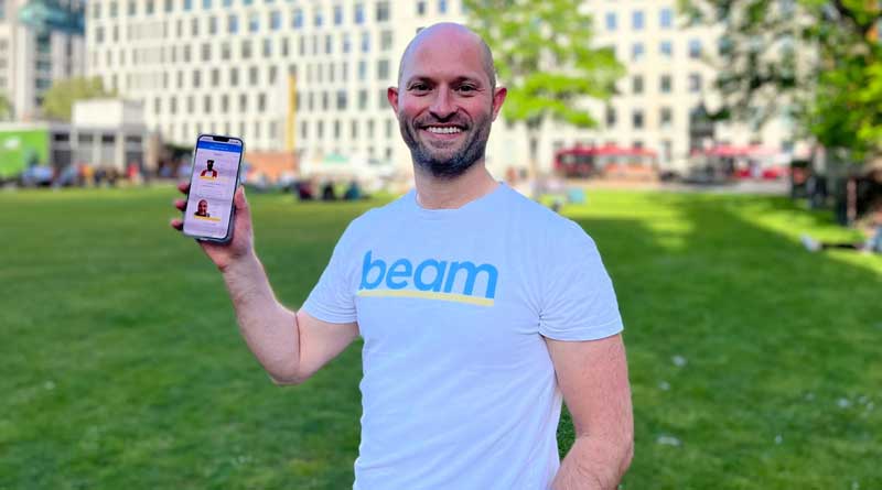 Alex Stephany holding out a smartphone displaying the Beam app