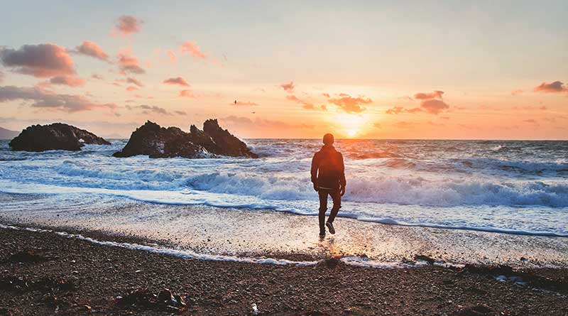 Man walking into the sea at sunrise